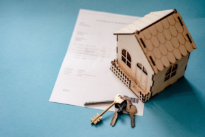 A house model with keys and an insurance document