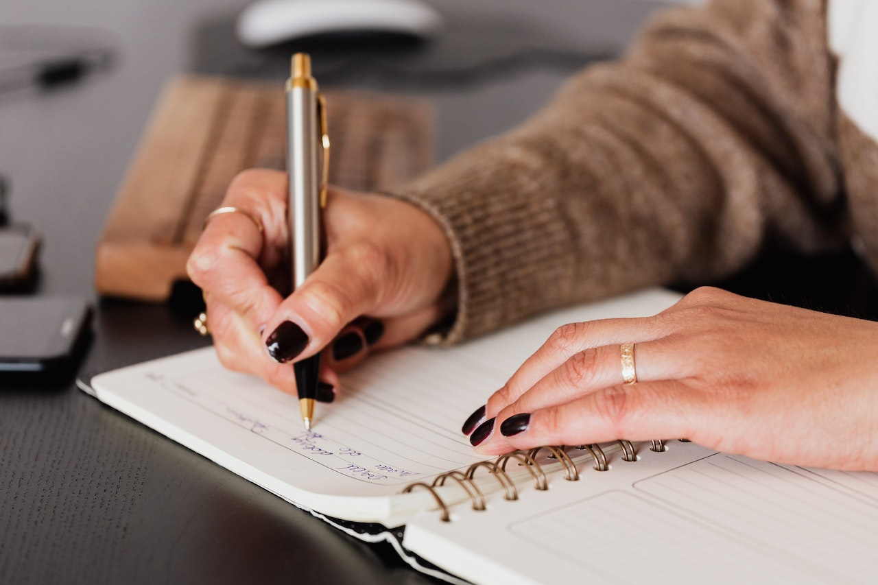 A Woman Writing with a Pen in a Notebook