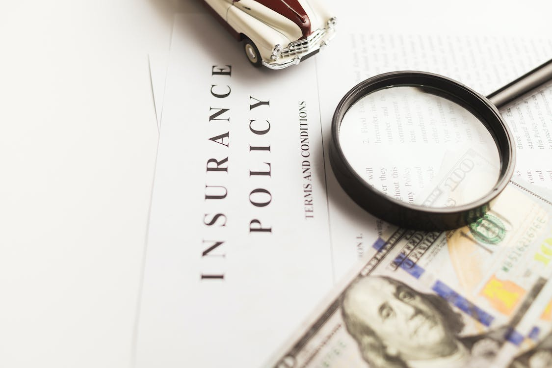 an insurance policy document with a magnifying glass and a dollar bill. 