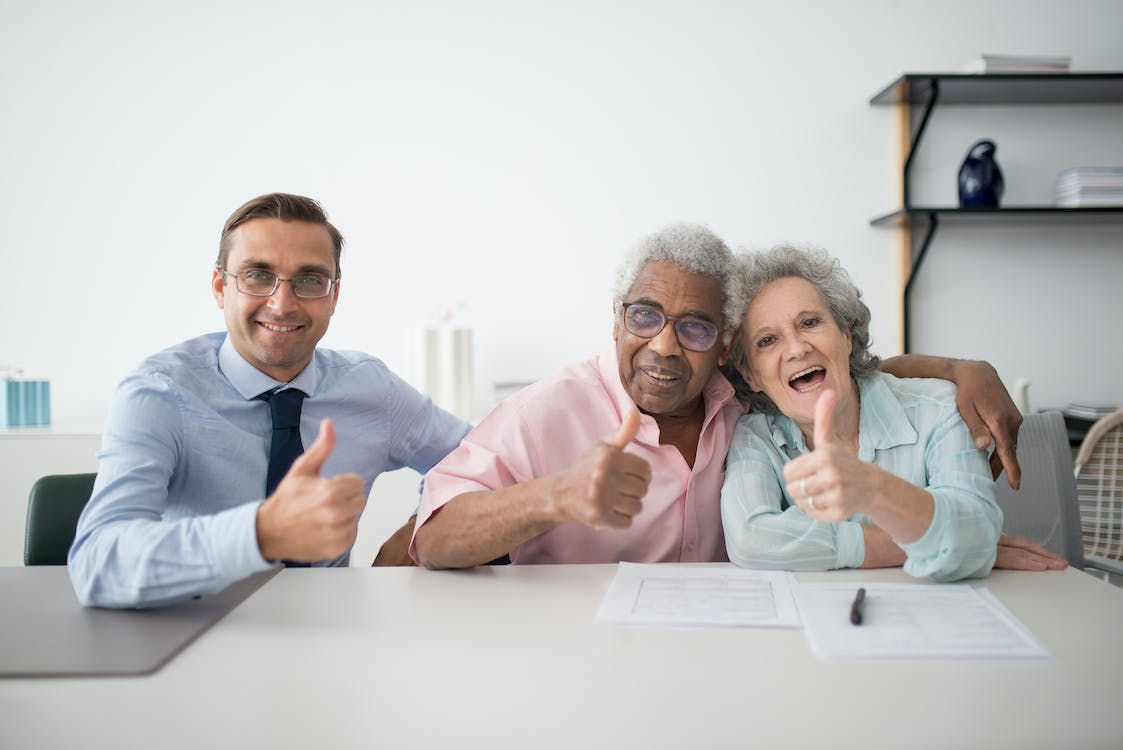 A public adjuster and senior couple giving thumbs up